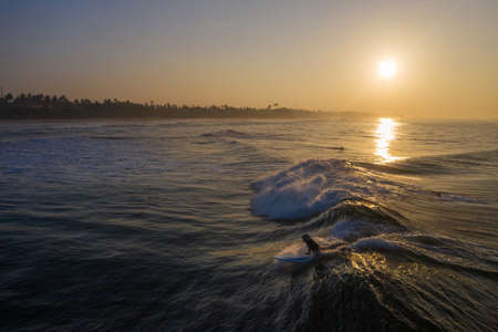 Aerial view of the beach and surfers on the island of Sri Lanka during sunriseの写真素材