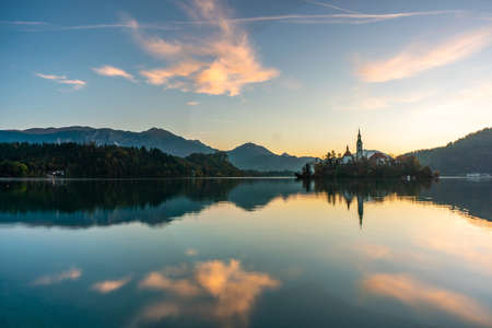 The famous Alpine Lake Bled (Blejsko jezero) in Slovenia, an amazing autumn landscape. Fabulous view of the lake, island with church, Bled Castle, mountains and blue sky with clouds, backdrop in the fresh airの写真素材