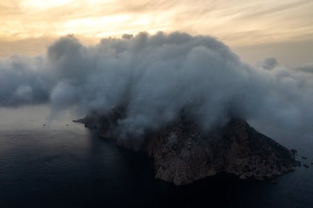 Mystical Aerial View of Ibizas Cloud-Covered Island at Sunsetの写真素材