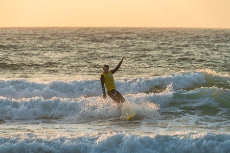 Surfer Riding Waves at Sunset in Peniche, Portugalの写真素材