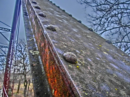 Structure beams of a old rusting bridge crossing a small stream.の写真素材