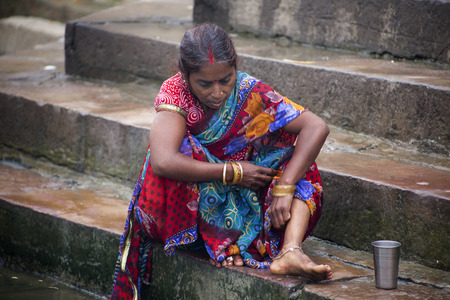 Woman bathing at the Ghat steps at the side of the Ganges River, Varanasi, India