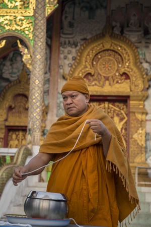 Chaing Mai region, Thailand - January 7, 2016: Buddhist Monk with string called a Sai Sin bracelet, a shortened length of Sacred Thread which has been blessed by monks for luck and fortuneのeditorial素材