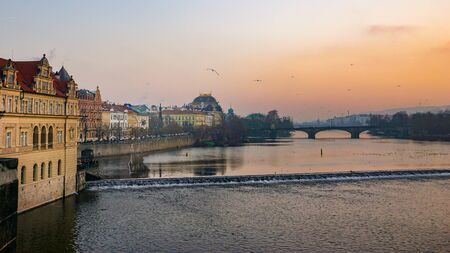 Sunset over the Vltava River in Prague, Czechia, lined by beautiful classical European buildingsの写真素材