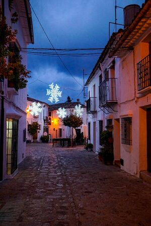 Twinkling, colorful Christmas lights decorate the darkened evening streets of Grazalema village, one of the pueblos blancos, or white villages of Andalucia in southern Spainの写真素材