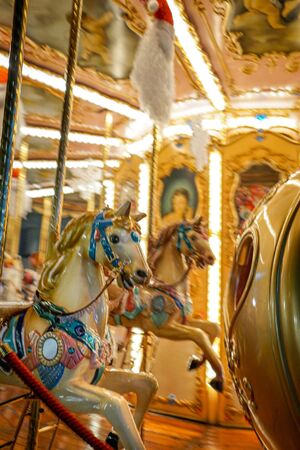 An old-fashioned carousel with white horses and bright lights is illuminated at night in Florence, Italyの写真素材
