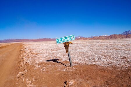 A signpost with a skull attached marks the dirt road across the Salar de Arizaro salt flats, near Tolar Grande in the high altitude desert of Saltas puna region in Argentinaの写真素材