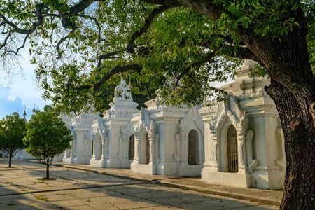 Shady trees and dappled light at dusk at Kuthodaw Pagoda, a Buddhist stupa at the foot of Mandalay Hill that holds the worlds largest book, in Mandalay in Myanmar, formerly known as Burmaの写真素材