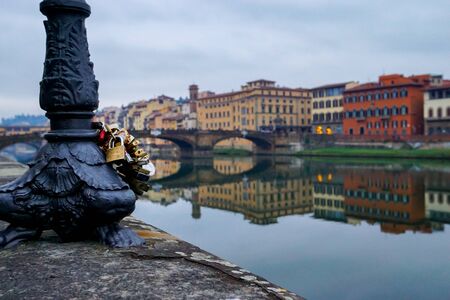 Love lock padlocks, symbolising eternal love, are attached to a lamp post on the banks of the River Arno in Florence, Italyの写真素材