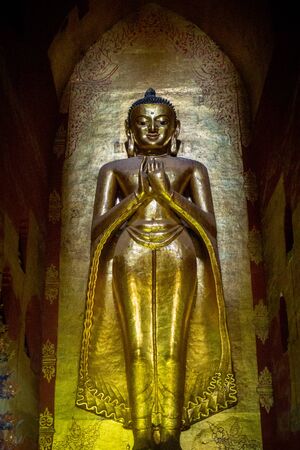 A golden Buddha statue stands towering inside the Ananda Temple in Bagan, Myanmar (Burma)の写真素材