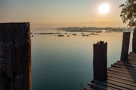 Sunrise view from the ancient teak wood U Bein Bridge that stretches across Taungthaman Lake at Amarapura, near the city of Mandalay in Myanmar (formerly called Burma)の写真素材