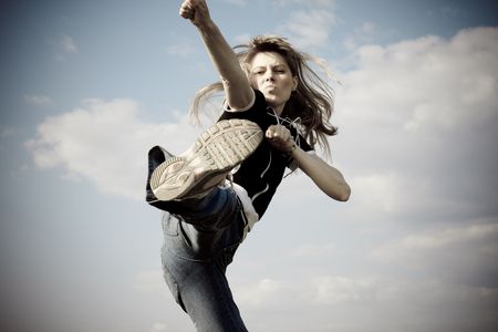 girl jumping outside with blue sky in backgroundの写真素材