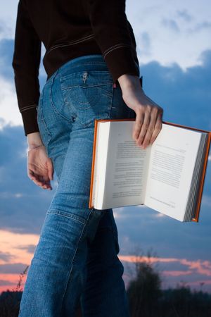 girl reading book and sitting outdoor with sky in backgroundの写真素材