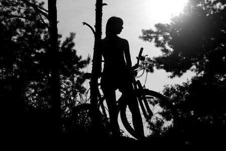 silhouette of the girl with bicycle in the forestの写真素材