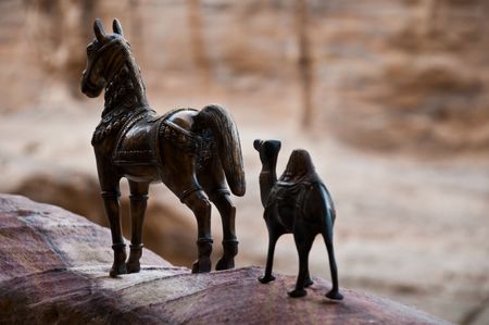 iron figurine of camel and horse with mountains in backgroundの写真素材