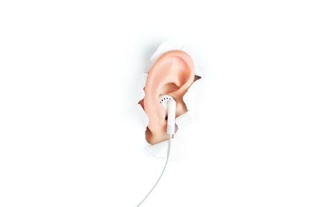 woman ear with headphones peeping out from white torn paperの写真素材