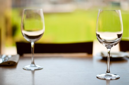 two empty glass goblets on wooden table in restaurant (extremely shallow depth of field, focus on front goblet)の写真素材