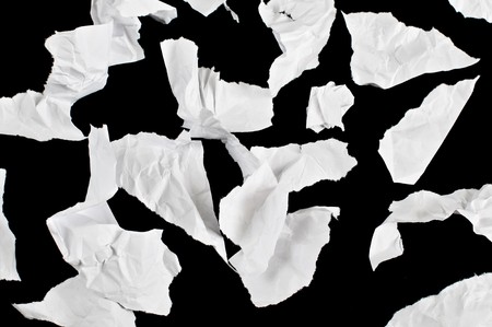 pieces of crumpled pieces of office paper isolated on black backgroundの写真素材