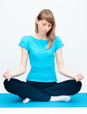 Fit young woman doing yoga exercise sitting in lotus poseの写真素材