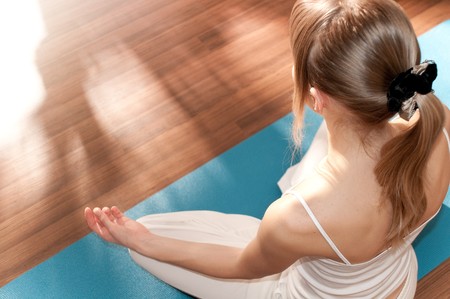 Fit young woman doing yoga exercise sitting in lotus poseの写真素材