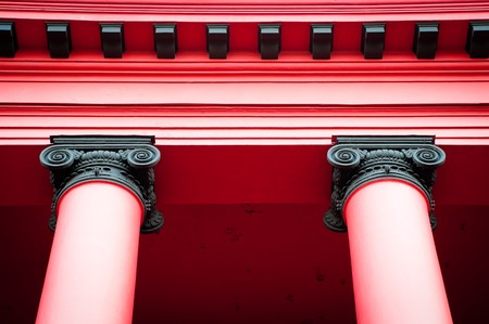 details of two beautiful red columns supporting roof of old red buildingの写真素材