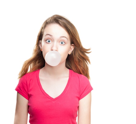 Beautiful and shocked or surprised young student girl blowing bubble from chewing gum. Looking into the camera. Isolated on white background.の写真素材