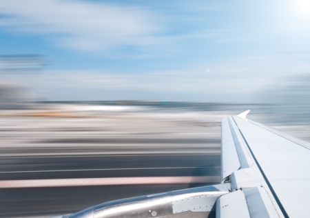 View of air plane wing during take off or landing. Motion blur of airport grounds and sky.の写真素材