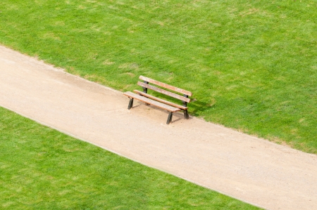 lonely bench standing on park walk with green lawn by sidesの写真素材