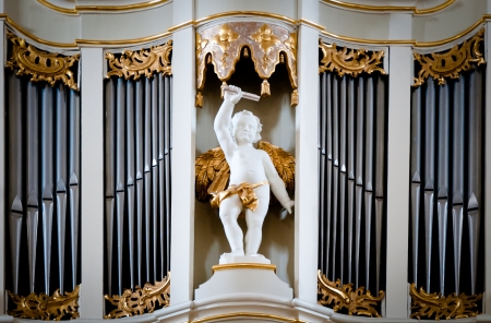 Statue of angel at old organ inside Vilnius cathedral, Lithuania, Europe. Sculpture of small angel boy with wings with metal pipes of organ in background.のeditorial素材