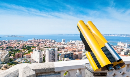 View on Marseilles cityscape from up high on sunny day. Tourist telescope in foreground and blue...