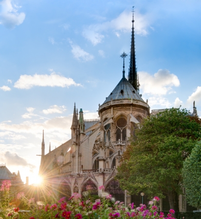 Rear view of Notre Dame De Paris cathedral at sunset with sun in the frame. Blue cloudy sky in background. Paris, France, Europe.の写真素材