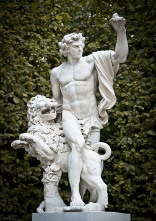 Classic sculpture in garden of Versailles. Beautiful young man with lion. Versailles, Paris, France,...