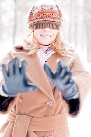 winter street portrait of young beautiful natural looking woman smiling and playing hide and seek with hat closing her eyesの写真素材