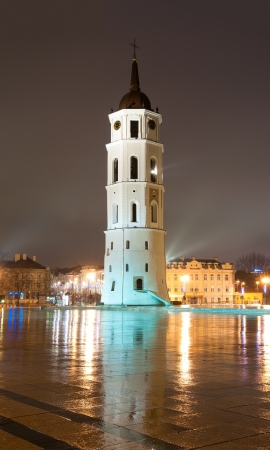 Vilnius cathedral bell tower at rainy night with reflection. Lithuania, Europe. Famous landmark. Place for copy in foreground and dark night sky in background.の写真素材
