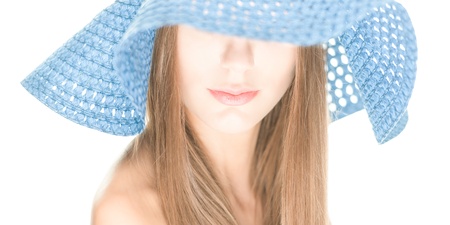 Portrait of pretty girl with her eyes under blue crocheted hat isolated on white backgroundの写真素材