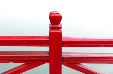 Part of bright red bridge closeup  Detail of wooden handrail with water in background  Beautiful symmetric construction outdoors  Wood structure of footbridge with railing  Architecture in asian styleの写真素材