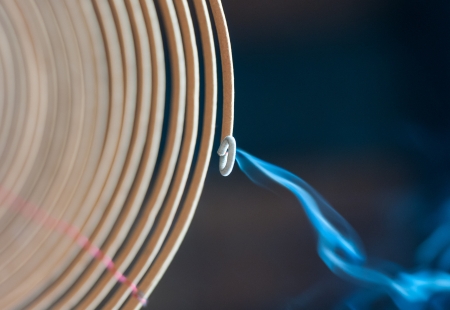 Close-up view of burning spiral incense stick with blue smoke going down on dark background  Traditional religious rituals in temple  Religion and traditions of East  Aroma and fragrance の写真素材