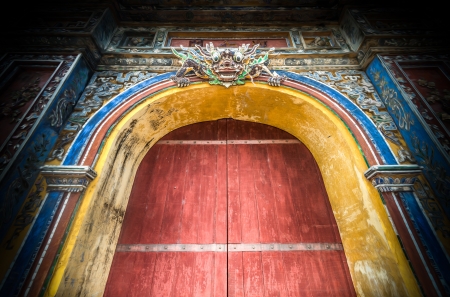 Beautiful wooden citadel gates in Hue city, Vietnam, Asia. Colored design of ancient building. Door with dragon face as symbol of protection. Famous destination for tourists. のeditorial素材