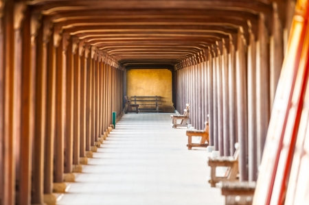 Arched doorway of Hue citadel, Vietnam, Asia. Yellow stone wall with entrance to hall. Wooden benches along wall, red ceiling and columns. Famous destination for tourists.のeditorial素材