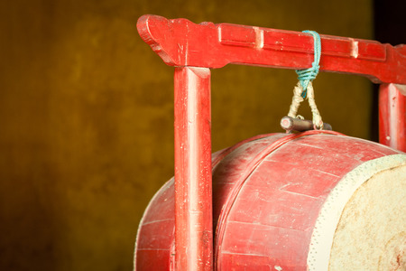 Detail of red drum hanging on red wooden rack in Buddhist temple. Religious attributes used in ceremony. Religion and traditions of East. Symbol of Asian faith and culture.の写真素材