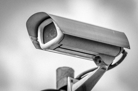 Security camera. Sky in background. Black and white with grain added.の写真素材