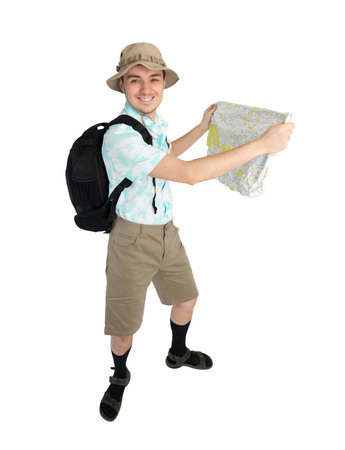 Happy man tourist in blue shirt, brown shorts and hat with backpack on his shoulders holding map. Traveler smiling and going to interesting tour. Isolated on white background.の写真素材