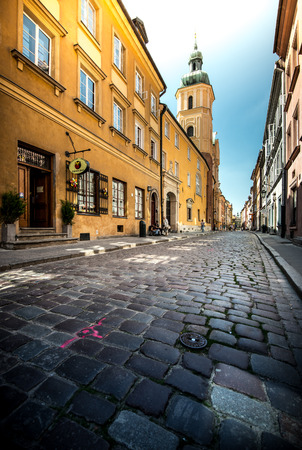 Old and narrow cobblestone street of Warsaw, Poland, Europe. Beautiful sunny day, colorful buildings. のeditorial素材