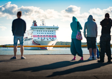 Big ferry ship arriving in port of Turku, Finland, Scandinavia, Europe. Liner with blue cloudy sky in background and people waiting in foreground.の写真素材
