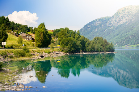 Norway country houses. Lake and mountains. Blue cloudy sky. Nordic, Scandinavia, Europe travelの写真素材