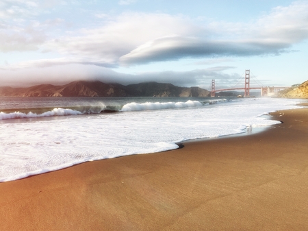 San Francisco Golden Gate Bridge in California USA. Beach and ocean in foreground, cloudy sky in...