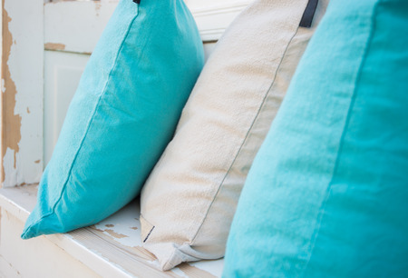 Colourful pillows on white wooden bench. Simple and clear design and colours