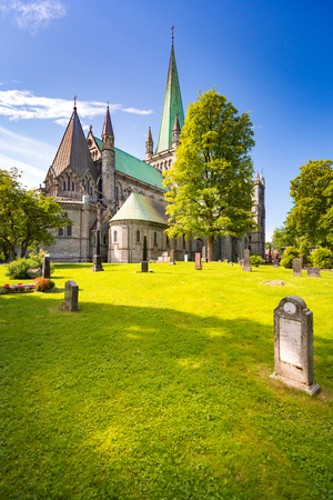 Old Trondheim cathedral. Norway, Europe travel. Blue cloudy sky in background and cemetery with green grass in foregroundのeditorial素材