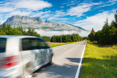 Car on road in Norway, Europe. Auto travel through scandinavia. Blue sky and mountain in backgroundの写真素材