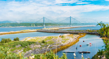 Panorama of bridge and car road in Norway, Europe. Auto travel through scandinavia. Blue cloudy sky, lake and bridge in background.の写真素材